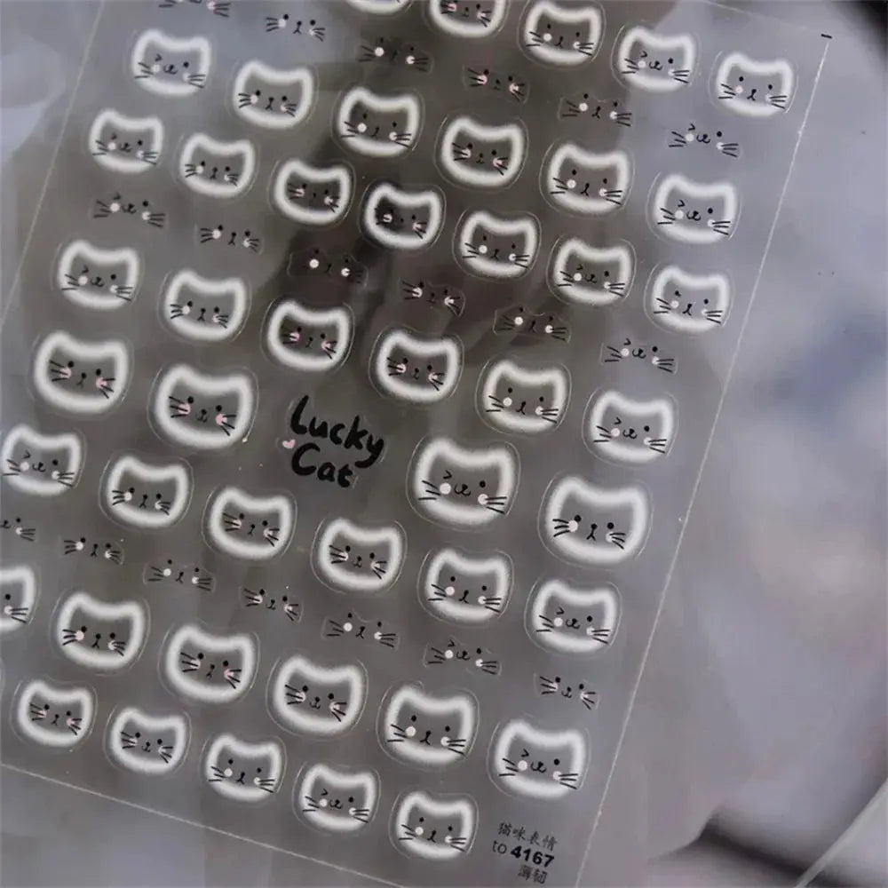 Cat-face nail art stickers sheet by Simples Market with white outlined cat heads on clear backing.