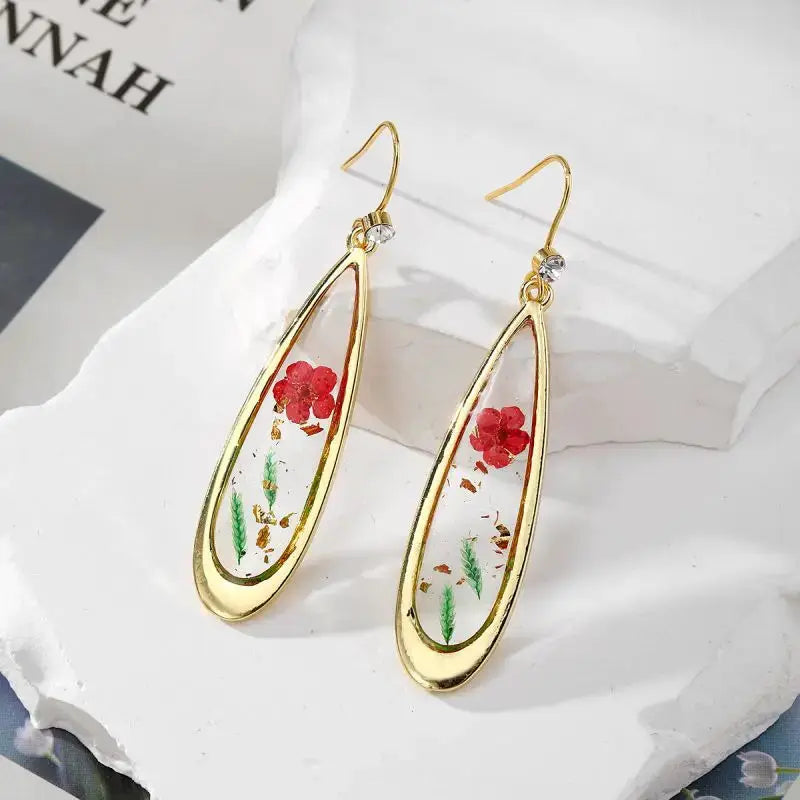 Simples Market pressed flower epoxy resin dangle earrings with gold-tone bezel, clear resin showcasing red flowers