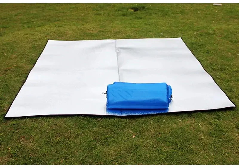 Simples Market camping foam foil mat on grass with blue carry bag.