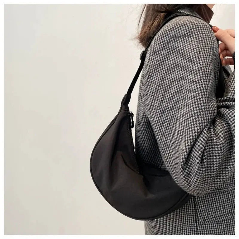 Nylon dumpling bag by Simples Market, lightweight black crescent crossbody shoulder bag worn over a grey houndstooth coat.