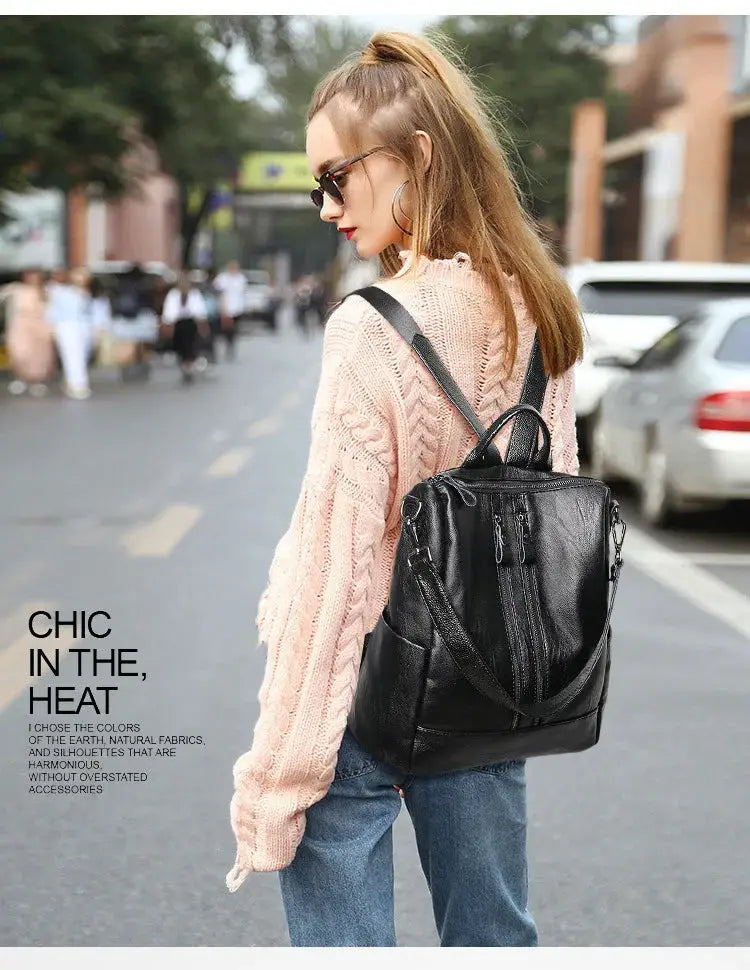 Black soft leather backpack with multiple zipper pockets, worn by a woman on a city street