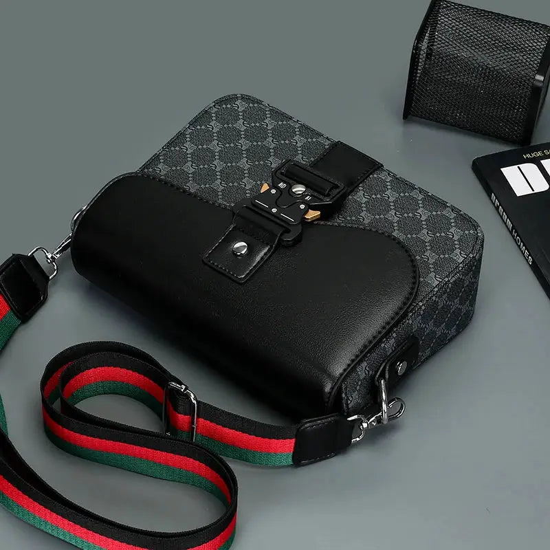 Crossbody bag with jacquard pattern, black leather accents, and adjustable green-red striped strap
