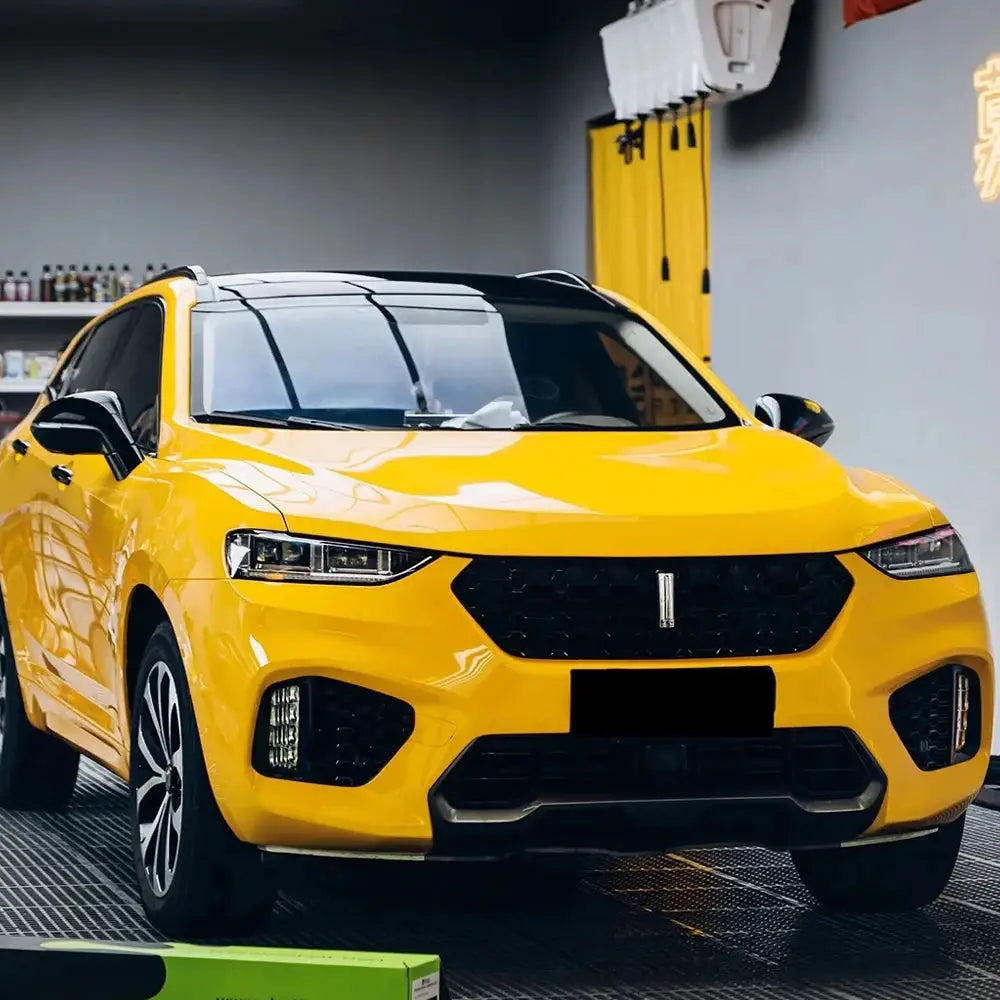 Glossy yellow car wrap film on SUV in a workshop, waterproof DIY auto decor film