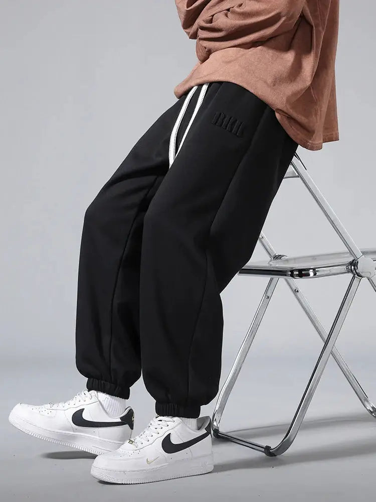 Men's black cotton/polyester joggers with white drawstring, elastic cuffs, baggy hip-hop style.