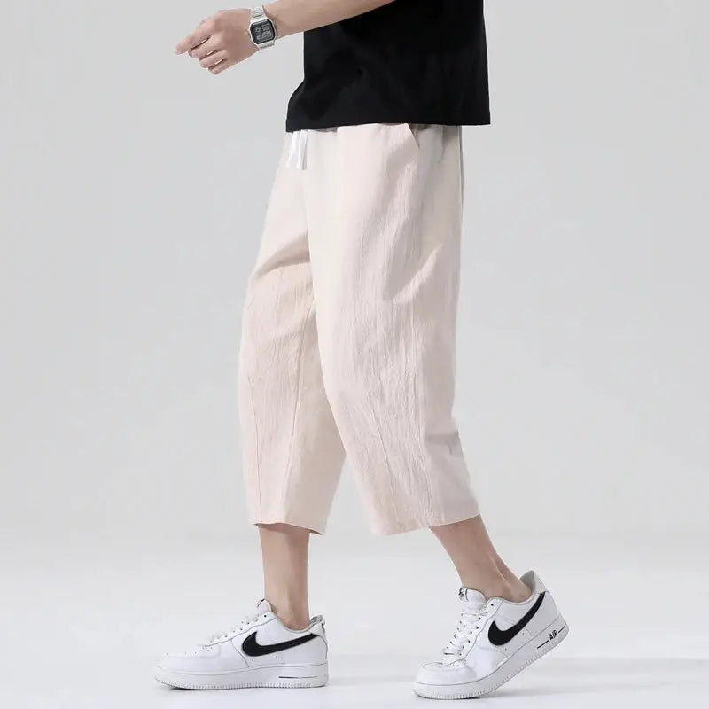 Men's light beige linen shorts with drawstring waist, paired with white Nike sneakers.