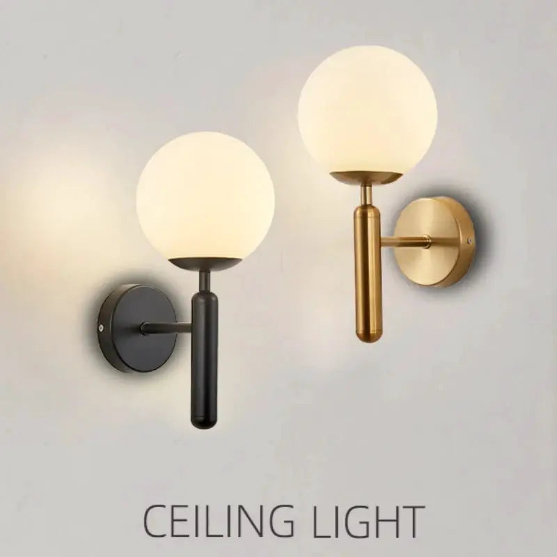 Modern indoor wall light pair with frosted glass globes in black and brass finishes.