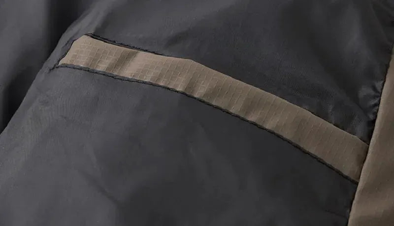 Winter men's down jacket close-up; dark gray shell with tan strap detail