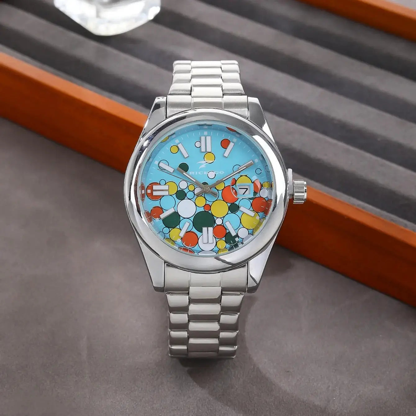Classic men's quartz wristwatch with stainless steel bracelet, blue dial with colorful circles and a date window.