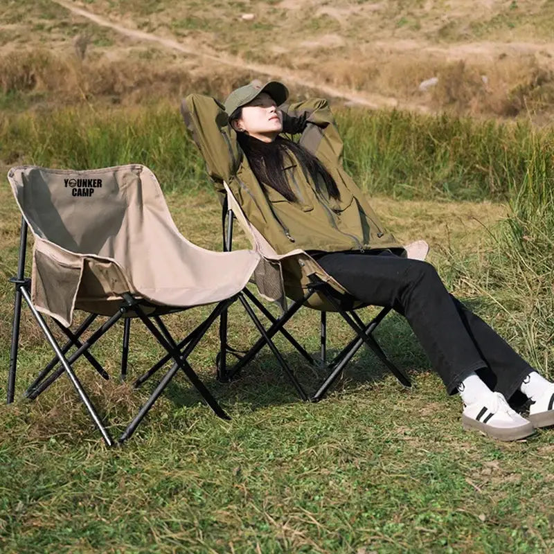 Outdoor folding moon chairs set of two beige chairs with black frames; one person lounging.