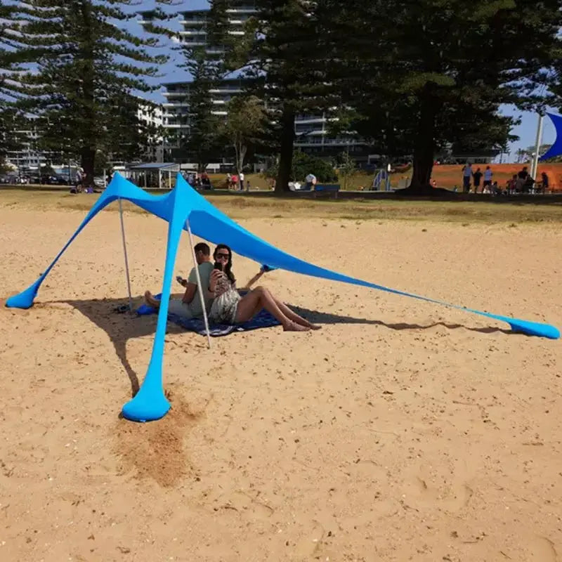Camping tent windproof pop-up beach canopy in blue by Simples Market on sandy beach; two people relaxing underneath.