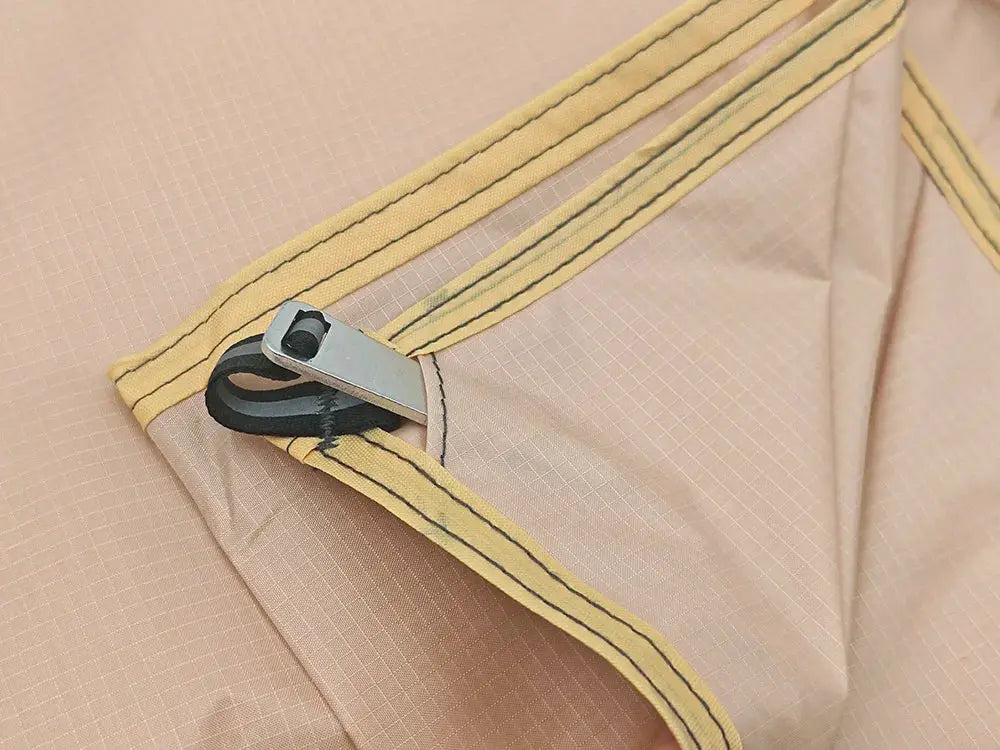 Waterproof camping mat with pegs, beige fabric with yellow trim and metal peg loop