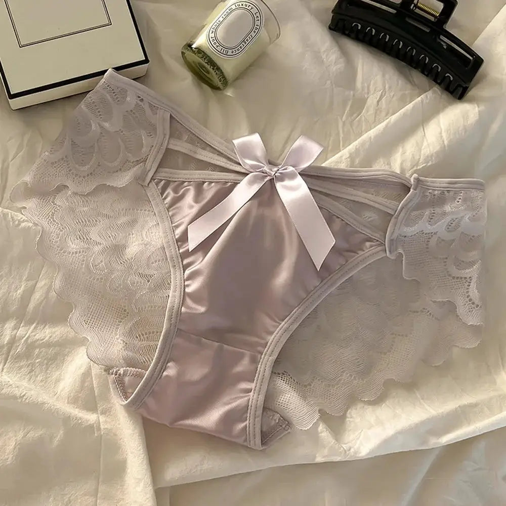 Women's lace-trim satin panties in pale pink with scalloped white lace sides and a satin bow.