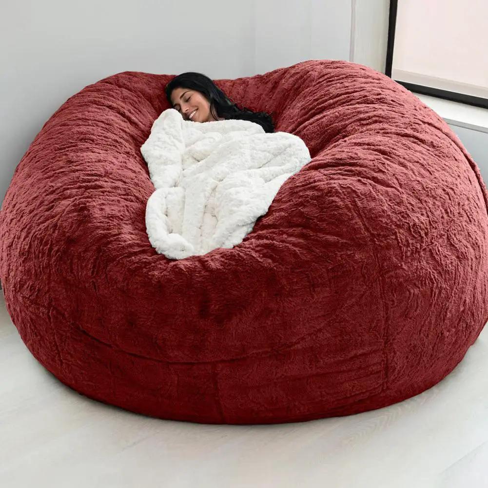 Giant red plush bean bag chair for floor lounging with a person resting on top