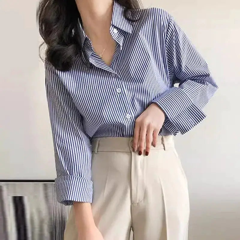Blue striped loose blouse with stand collar and long lantern sleeves, paired with beige high-waisted trousers.