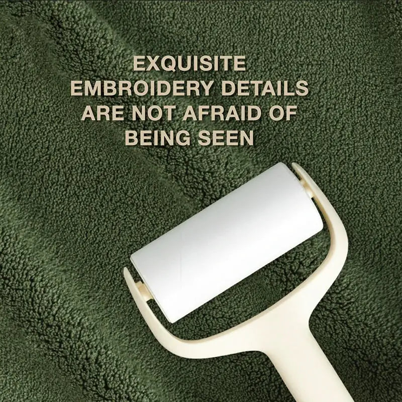 Lint roller with white adhesive sheet and beige handle on a green plush background.