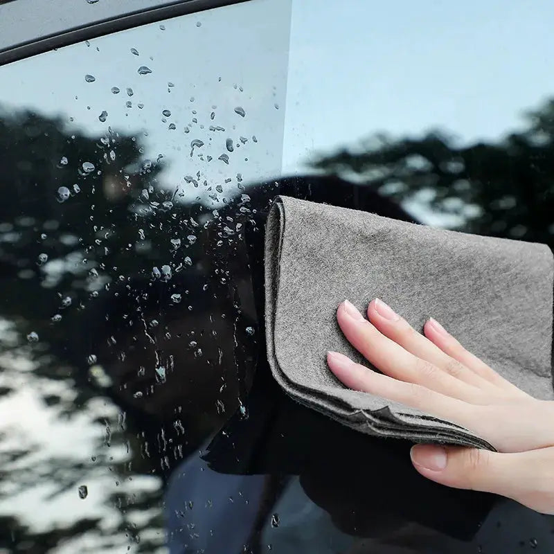 Gray microfiber cleaning cloth wiping glass window; thick, reusable towel.
