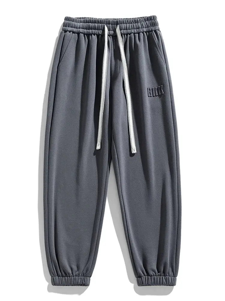 Men's gray cotton/polyester jogger sweatpants with white drawstring, cuffed ankles, loose fit.