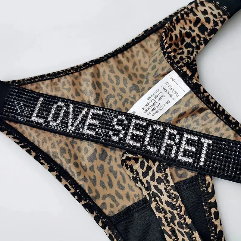 Leopard print low-waist thong with rhinestone waistband spelling LOVE; black mesh trim, women’s G-string