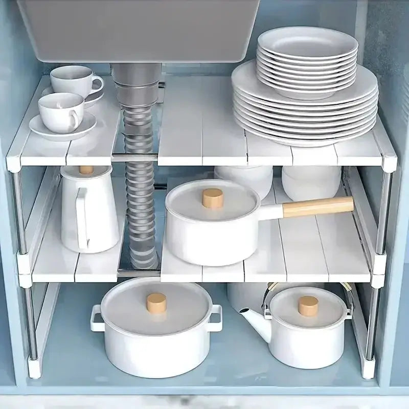 Stackable wardrobe storage rack, white multi-tier organizer inside a cabinet with plates, pots, kettle and cups.