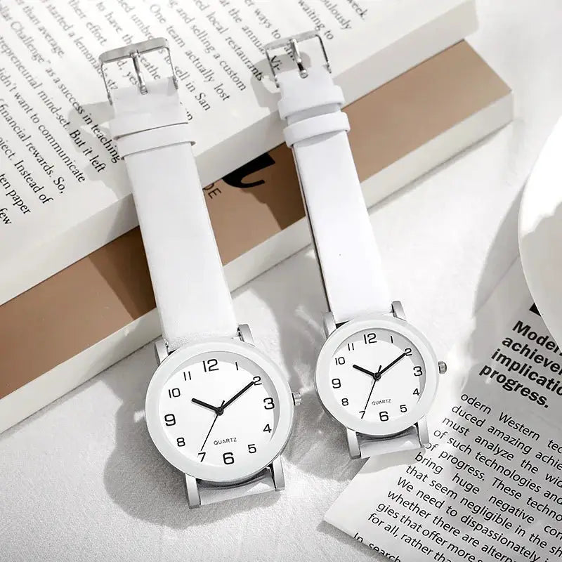 Pair of white leather strap watches with silver cases and black Arabic numerals; quartz movement.
