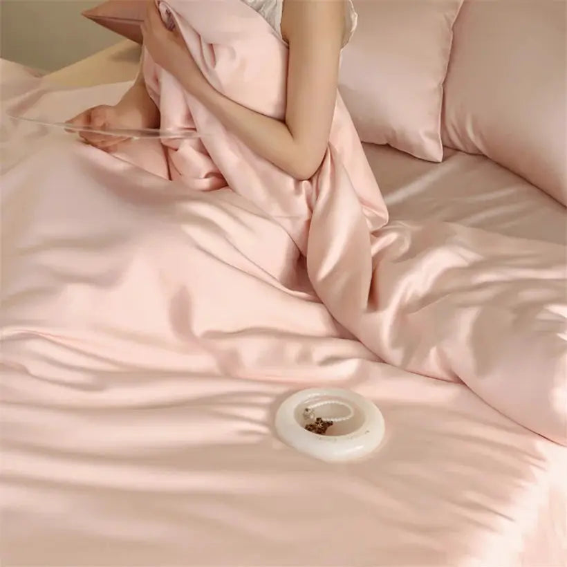 Mulberry silk bedding set in pink on bed with pillowcases, person wrapped in silk