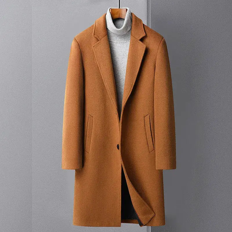 Men's long camel wool coat with front pockets and lapels, worn over a gray turtleneck