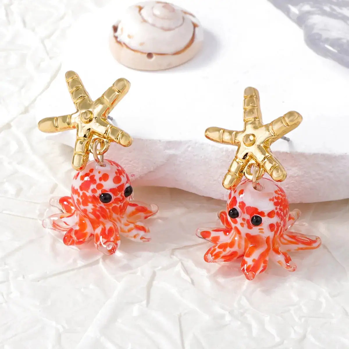 Pair of gold-tone starfish earrings with glass orange octopus drops