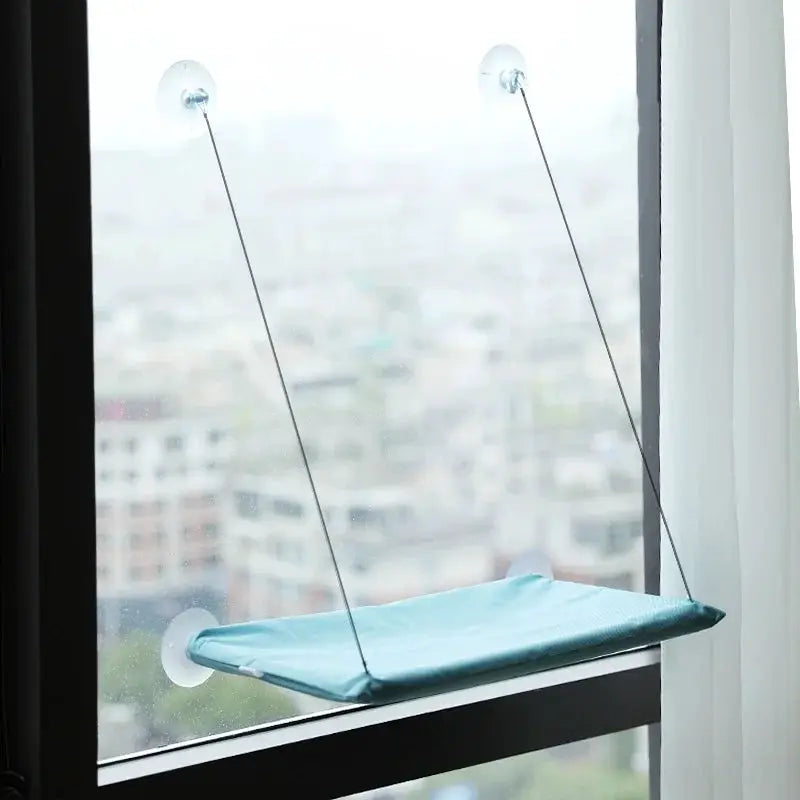Cat window hammock in light blue fabric, suction-cup mounted.