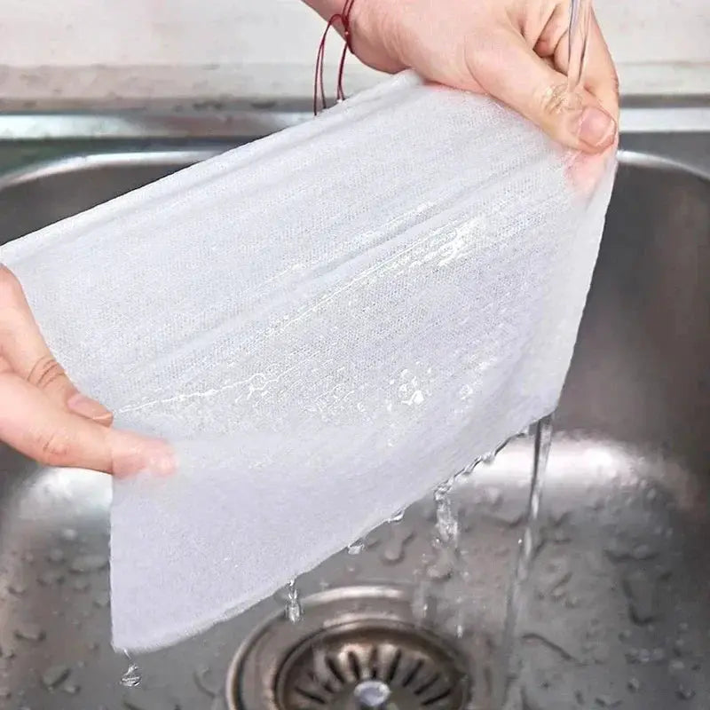 White non-woven kitchen cleaning cloth being rinsed under running water