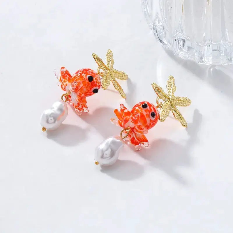 Cute octopus long-drop earrings with orange marble glass octopus, gold starfish accents, and white marbled pearl charms