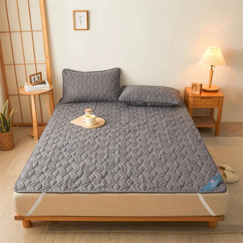 Simples Market waterproof breathable noiseless mattress protector on a grey quilted bed.