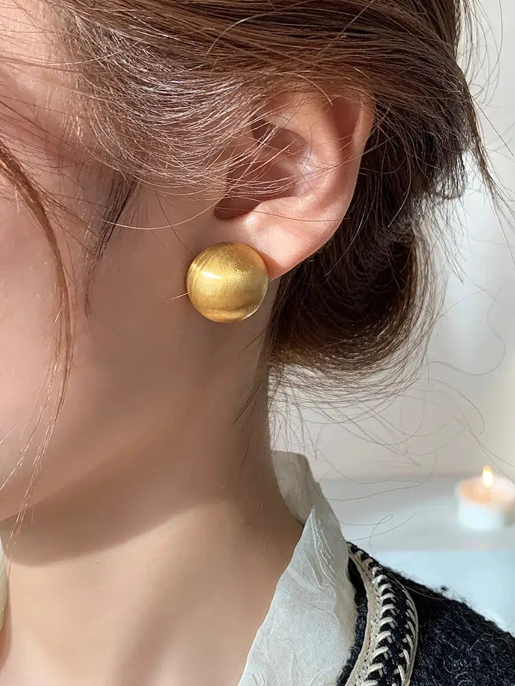 Earrings gold brushed metal stud with a large circular disc design