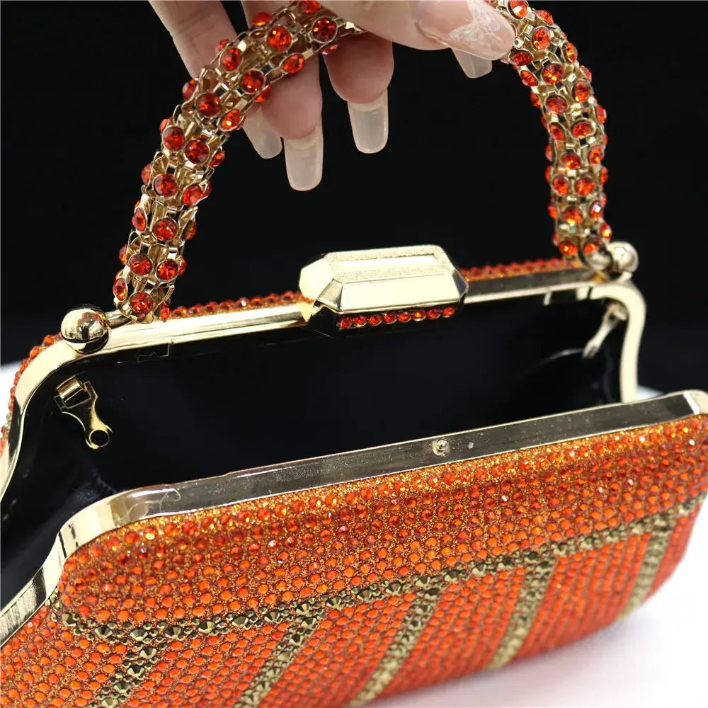 Rhinestone embellished evening clutch with orange-red stones, gold frame, and long chain handle