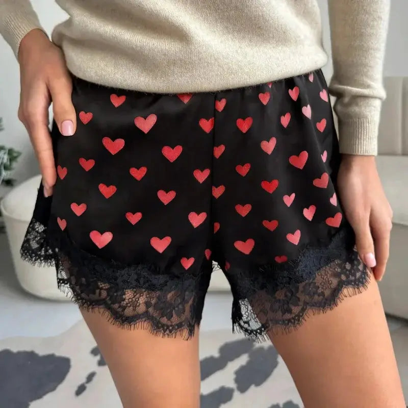Women's black satin shorts with red heart print, elastic waist, and lace trim hem