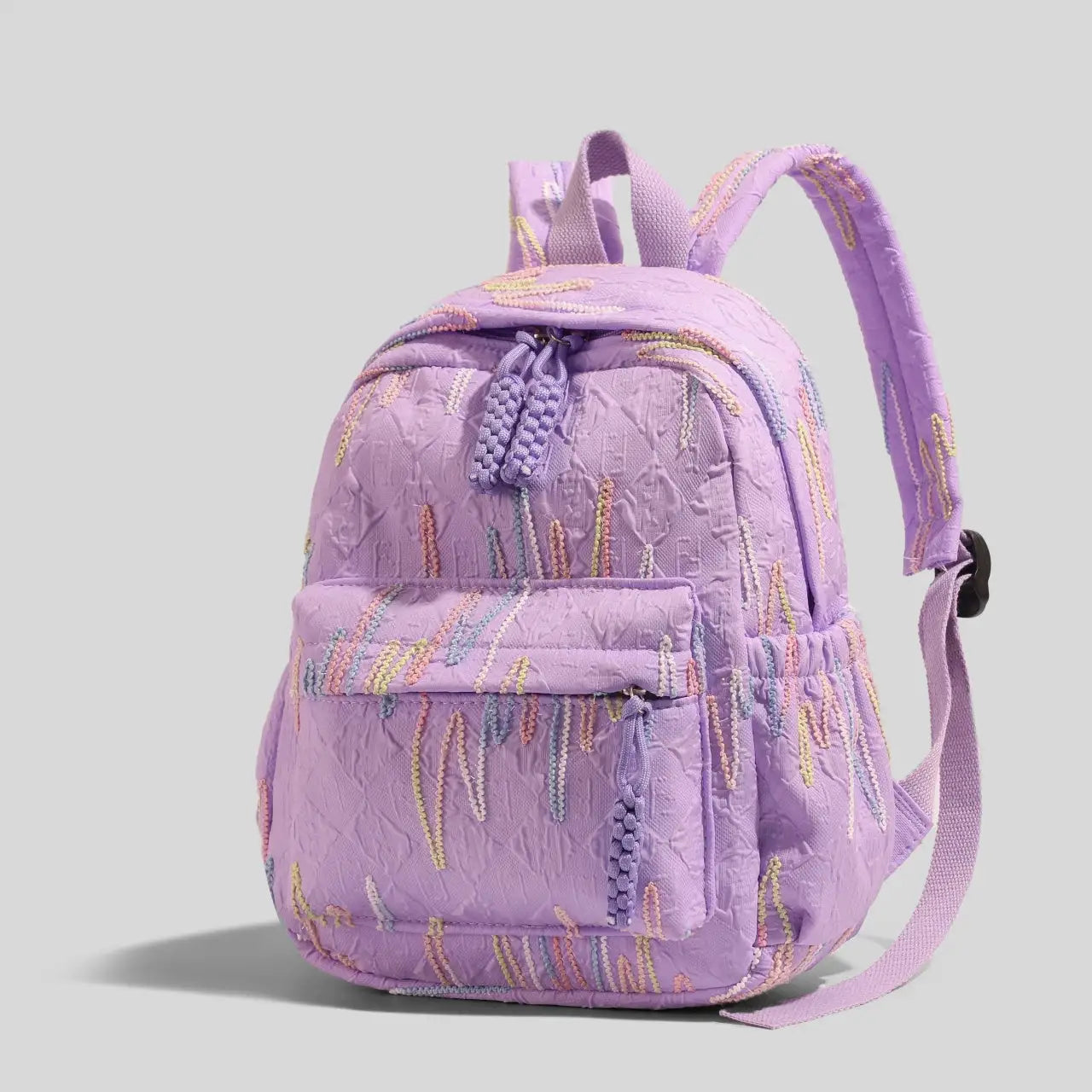 Women's mini backpack in lavender quilted fabric with pastel embroidery, zipper closure, adjustable straps.