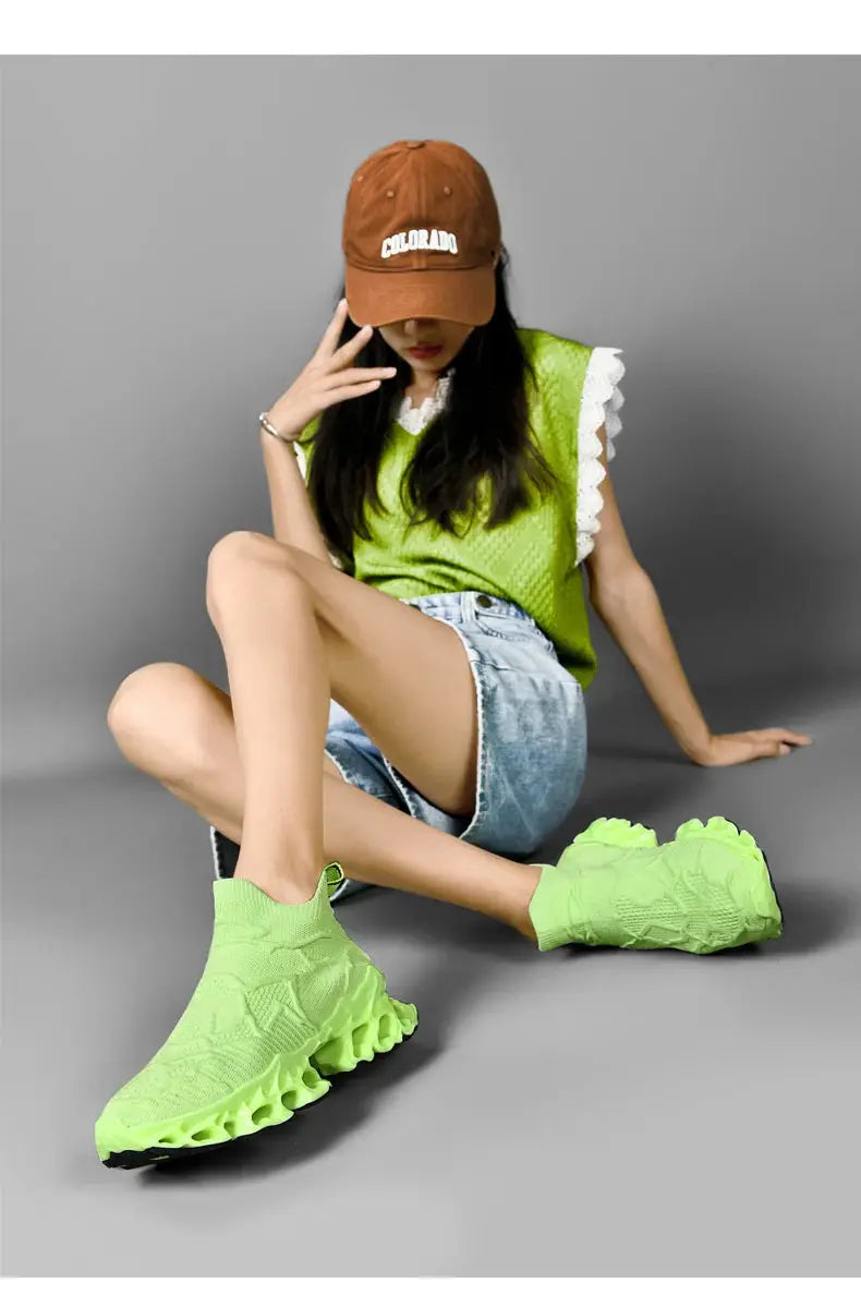 Men's neon green knitted sneakers with a sculpted chunky sole worn by a model in lime top and denim shorts