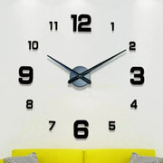 Analog wall clock with oversized black numerals on a white wall, blue center disc and metal hands above a yellow sofa.