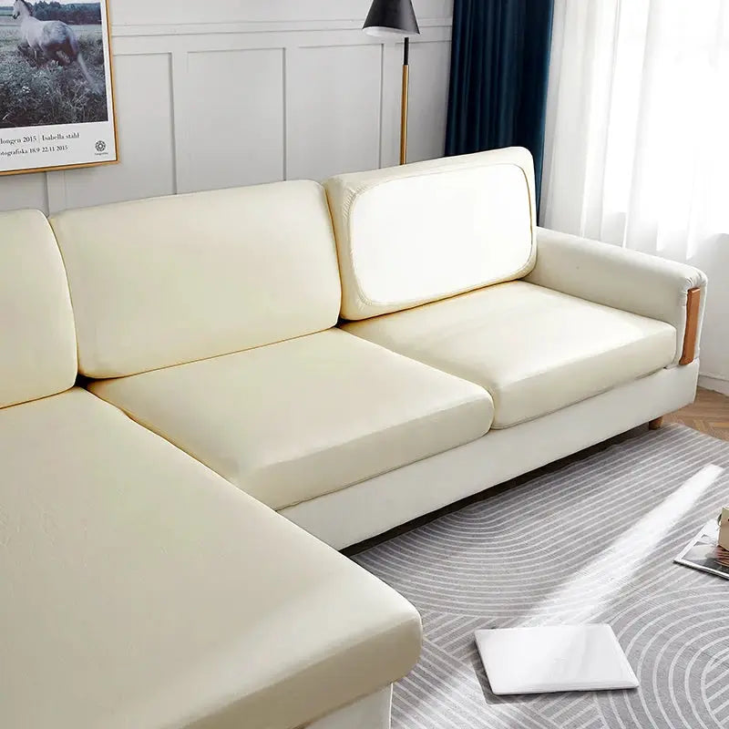 Corner sofa slipcover in cream waterproof PU fabric with elastic stretch fit.