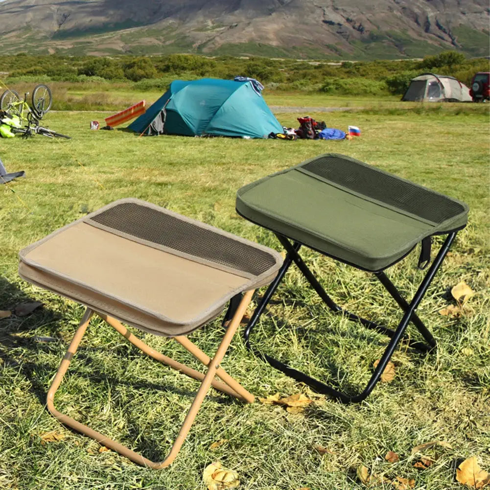 Two folding camping stools in beige and olive green on a grassy campsite with tents in the background.