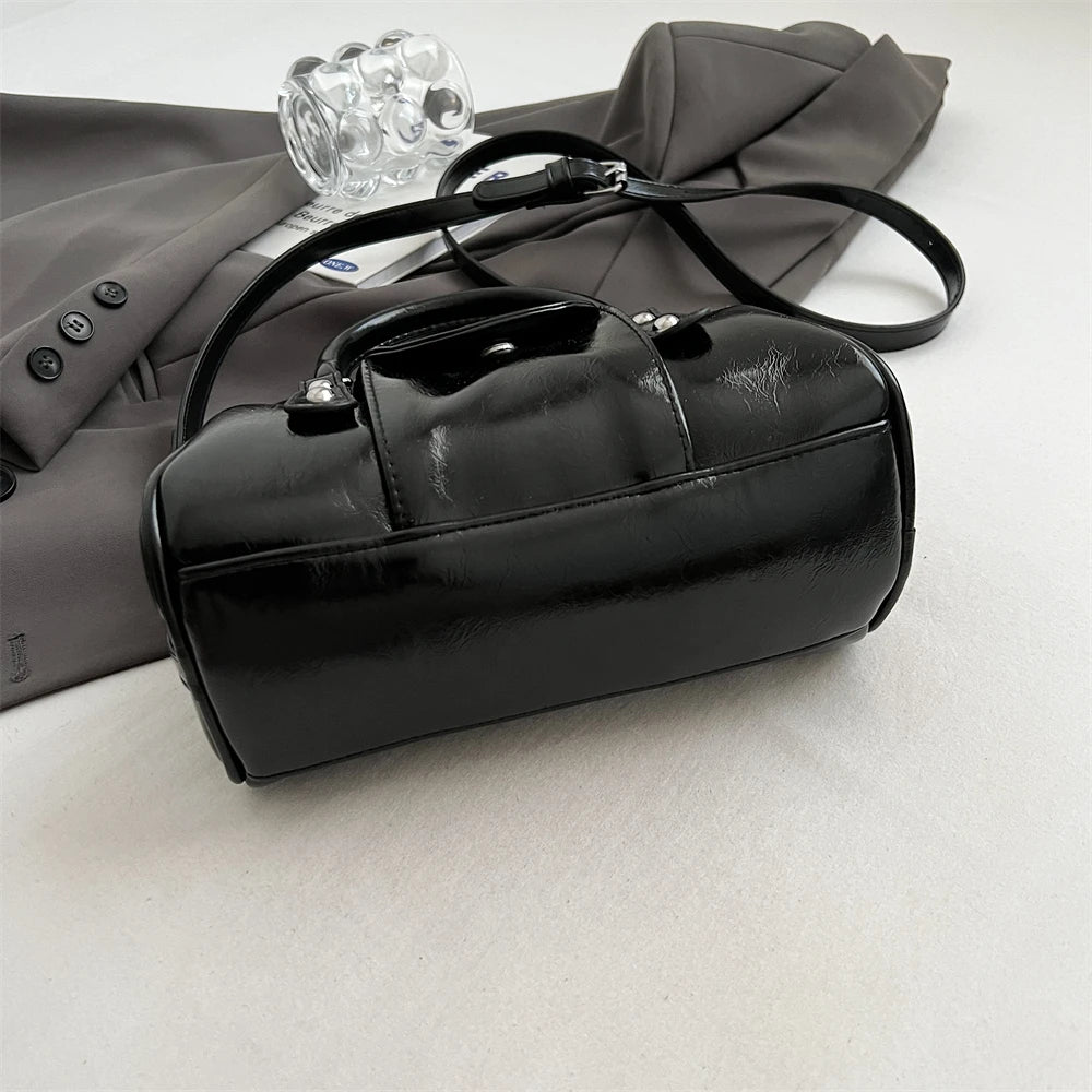 Mini top-handle bag by Simples Market in black patent leather with crossbody strap.