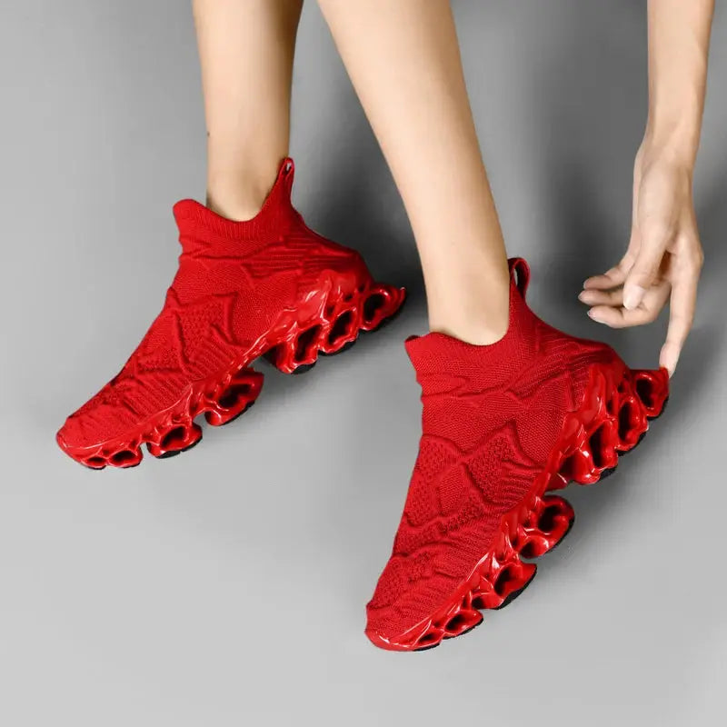 Pair of red knit sneakers with distinctive hollow pod soles, casual running shoes.