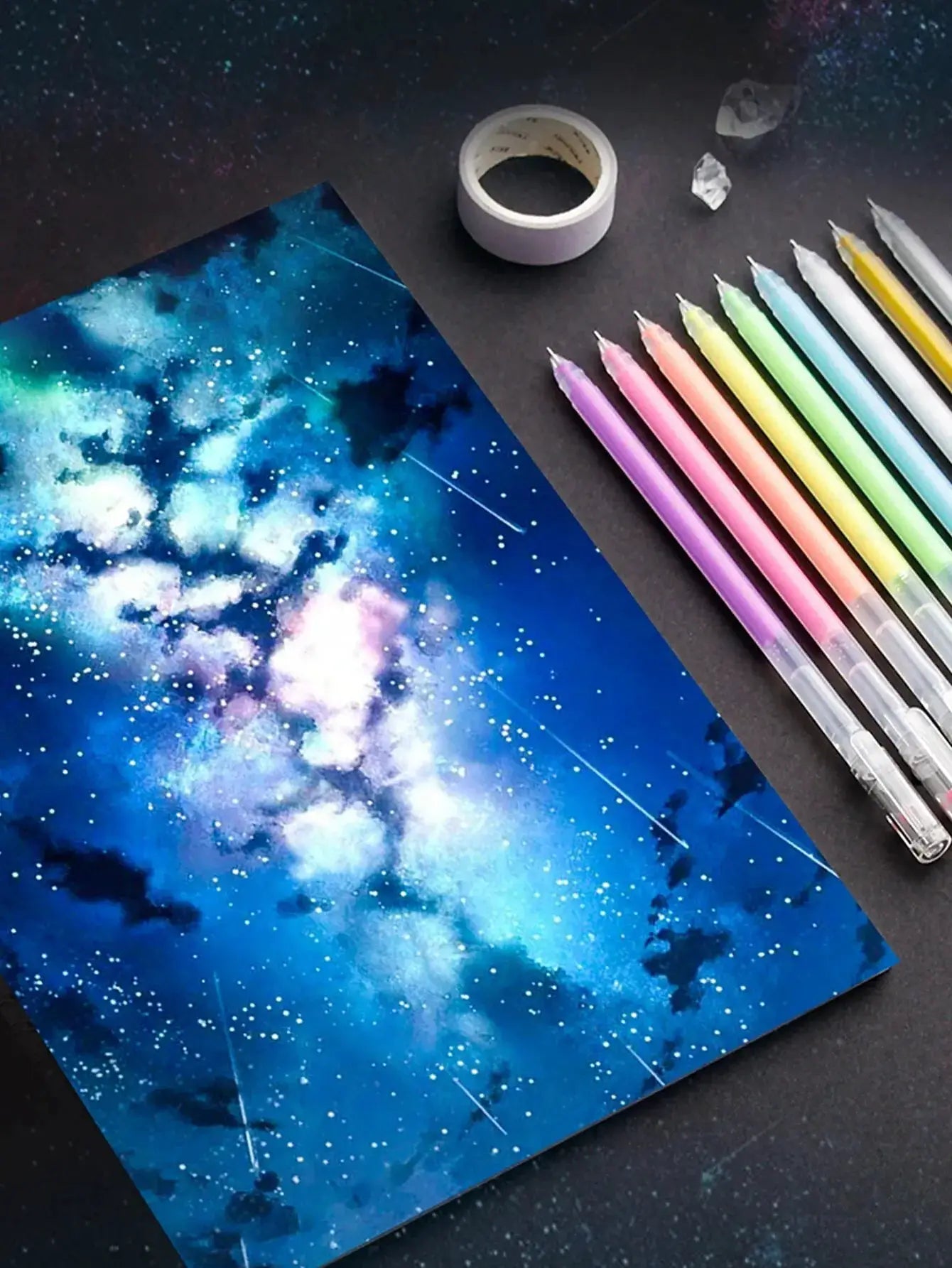 12-color gel pen set with fine 0.5mm tips in pastel shades beside a galaxy-pattern drawing sheet