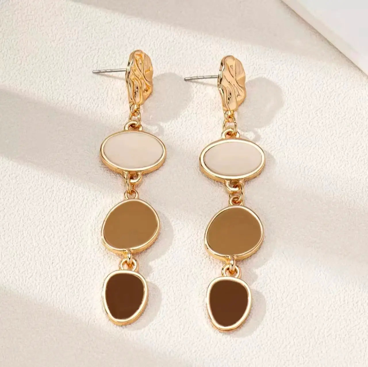 Gold-tone drop earrings with three linked oval cabochons in white, cream, and brown