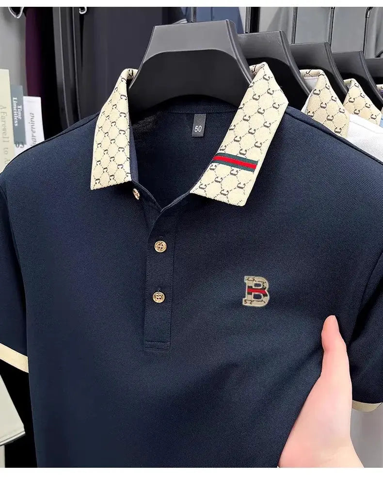 Navy polo shirt with beige patterned collar and embroidered B logo on chest; lightweight short sleeve