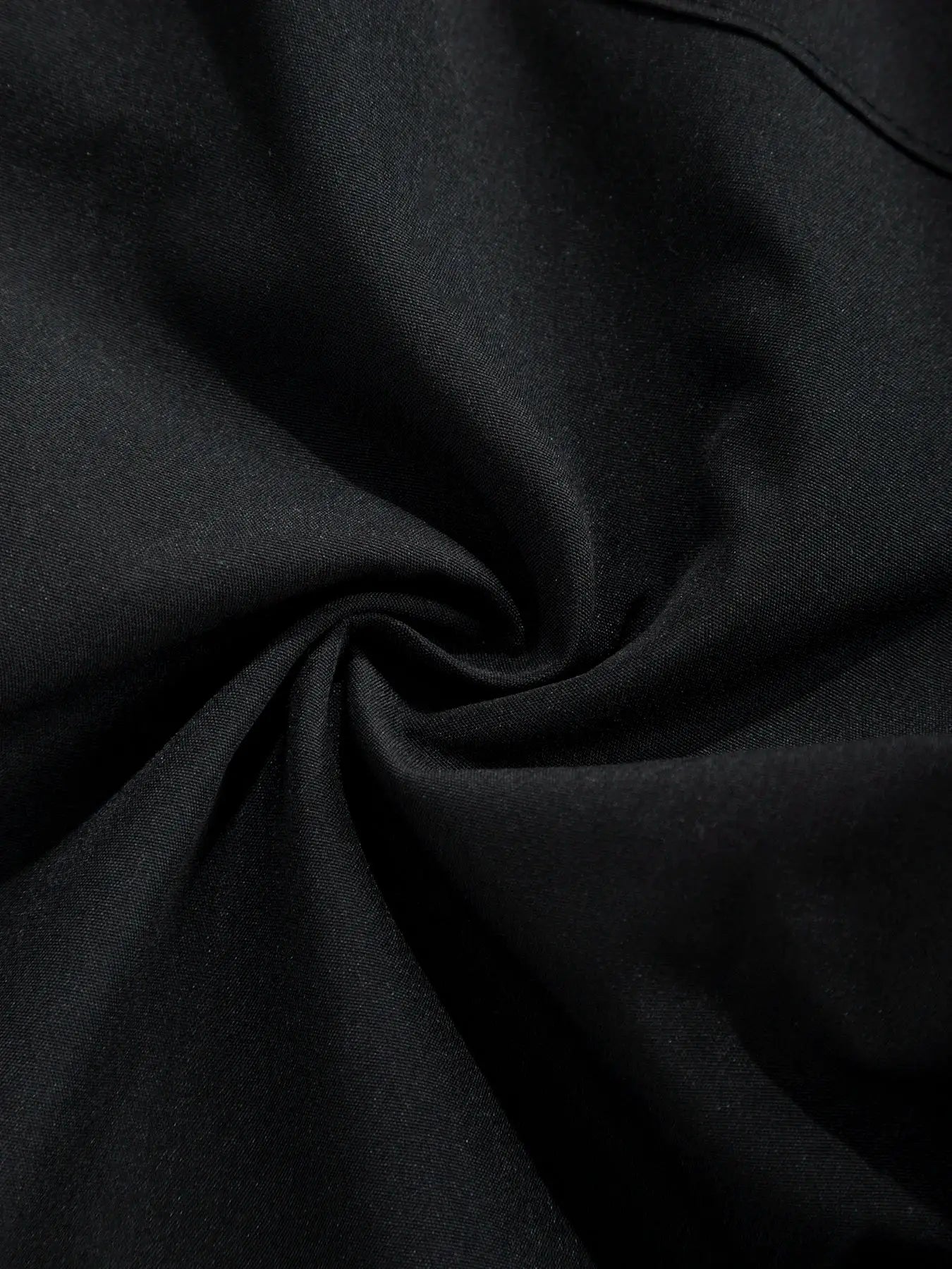 Men's cargo pants fabric close-up in black, smooth textile