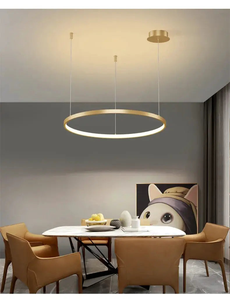 Minimalist gold circular LED pendant light over a white marble dining table