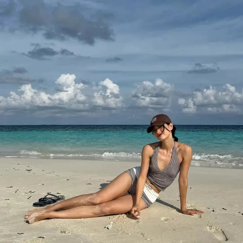Two-piece bikini set with deep-V halter top and high-waisted black-and-white checkered briefs, beach-ready.