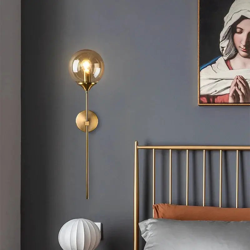 Modern glass wall lamp with gold finish and round globe bulb, bedside wall sconce