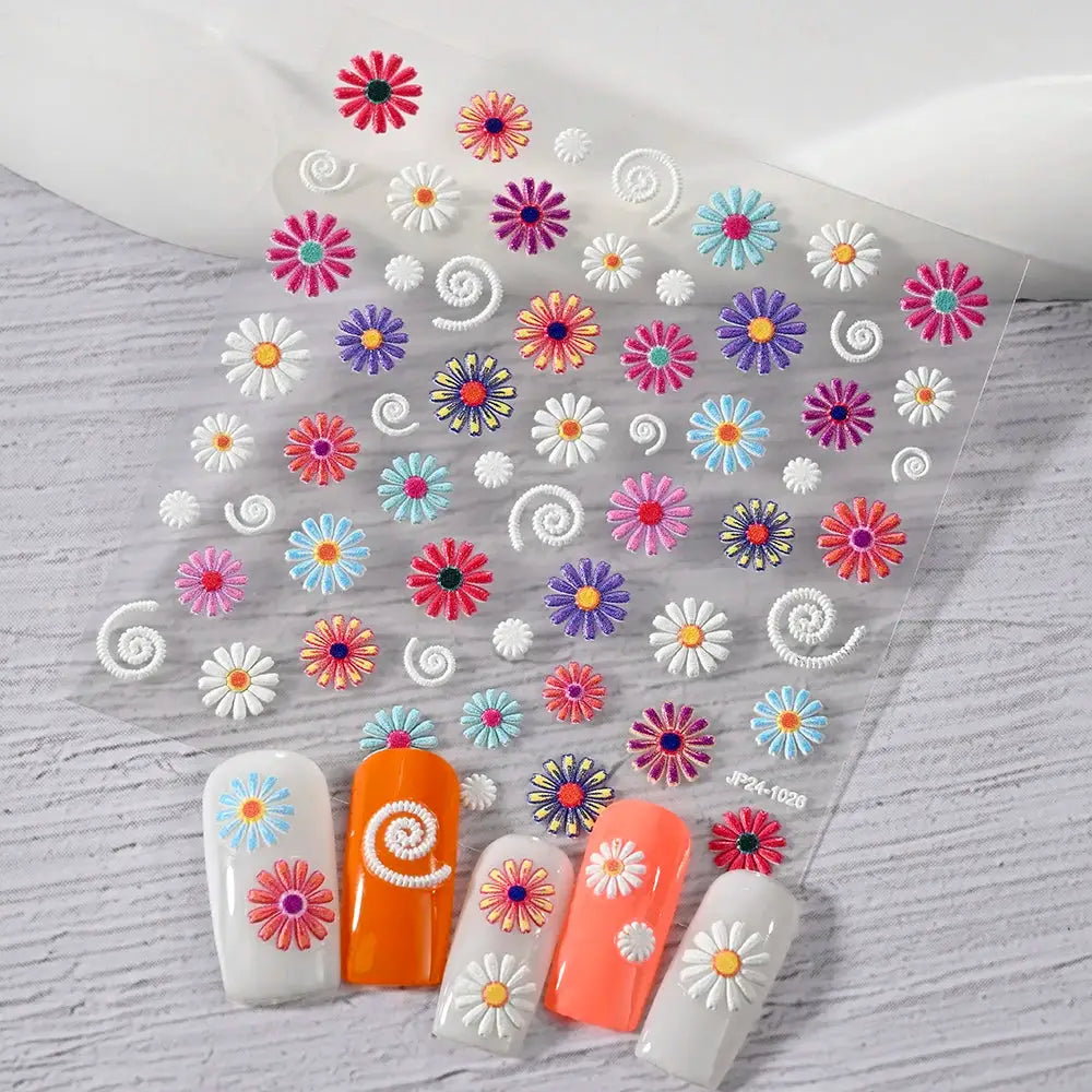 Nail art sticker sheet by Simples Market; colorful daisy decals with white spiral accents for summer manicure