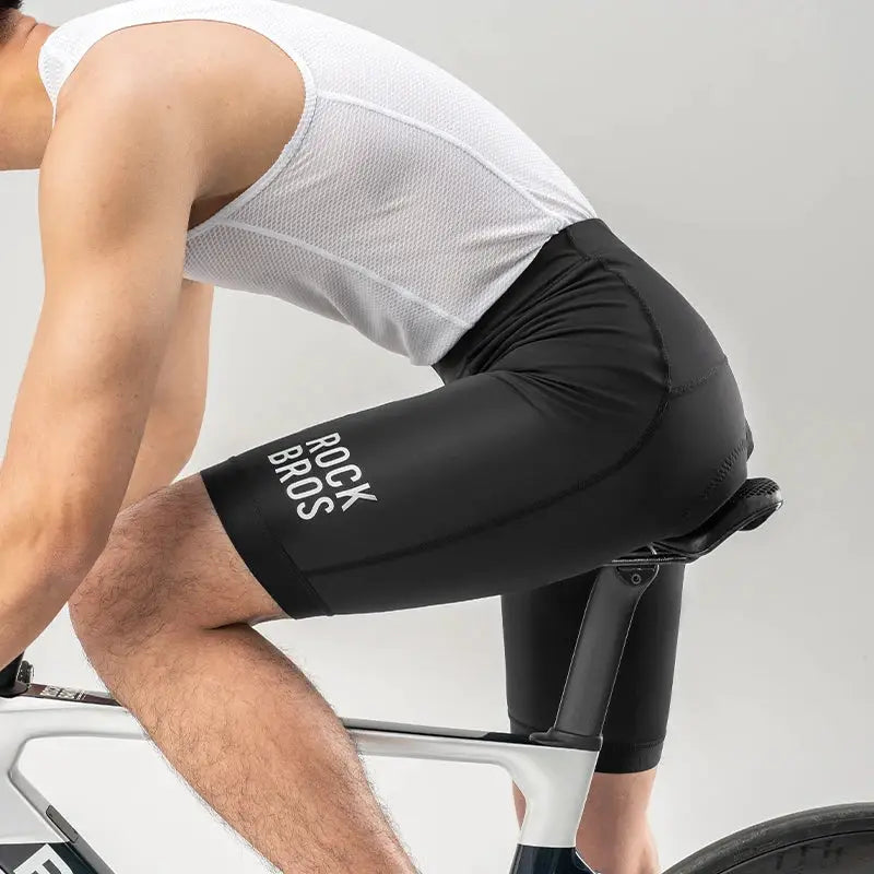 RockBros men's cycling shorts, black with white logo, worn on a road bike
